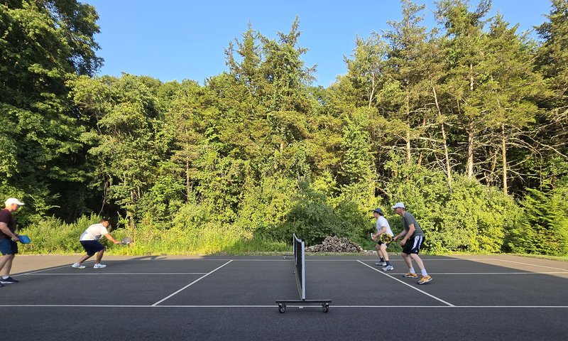 The Crew founding crew playing doubles on an outdoor court